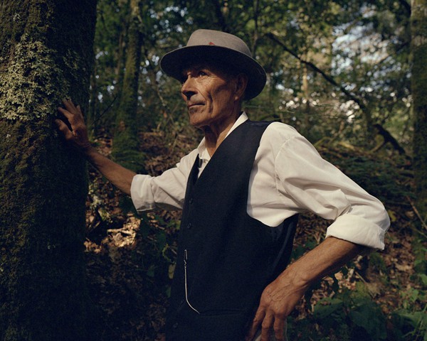 Un habitante rural de Galicia se apoya en un árbol mientras observa una protesta teatral que aborda los problemas del agua
										y se opone a la construcción prevista de la fábrica de Altri en Palas de Rei. Agricultores y vecinos temen que el consumo
										de agua de la fábrica —estimado en 46 millones de litros diarios— pueda alterar la reconocida producción quesera de la
										región. Palas de Rei es conocida por su elaboración artesanal de quesos, una parte fundamental del patrimonio cultural y
										de la economía local, que se enfrenta a posibles amenazas derivadas de la actividad industrial y del impacto ambiental que
										podría traer el proyecto de Altri.