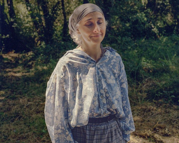 Martina, profesora de secundaria de Teo, posa en Palas de Rei durante un descanso de la obra teatral “Son de Aldea”, que
										este año estuvo dedicada al agua. Este festival, que cada año aborda una temática diferente, se centró en 2024 en una protesta
										original y pacífica contra la instalación de la fábrica de celulosa de Altri. Esta industria supone una grave amenaza para
										el ecosistema rural y la biodiversidad de Palas de Rei, al afectar a los recursos hídricos y fomentar la expansión de monocultivos
										de eucalipto, una especie invasora que degrada el suelo y desplaza la flora autóctona. A través de iniciativas como esta
										obra, la comunidad local busca concienciar sobre los riesgos que Altri representa para la sostenibilidad ambiental y social
										de la región.