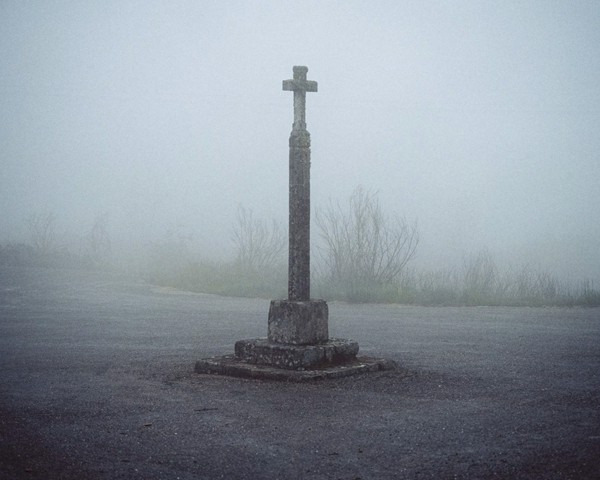 Galicia es una tierra con una profunda tradición religiosa y mística. Una de las leyendas más conocidas de Galicia es la Santa
										Compaña, una procesión de almas de difuntos en pena que vaga por aldeas y bosques durante la noche. Estos espíritus,
										cuyas identidades permanecen ocultas bajo capuchas, siguen en silencio a su guía, llevando una cruz y una vela encendida.
										Según la leyenda, si te encuentras con la Santa Compaña, no debes mirarla hasta llegar a un cruceiro, porque si la miras te
										convertirás en un alma errante y caminarás con la Santa Compaña por el resto del tiempo.
										Los cruceiros se levantan en encrucijadas o cerca de ermitas, iglesias y cementerios y, según la tradición, su presencia te protegerá
										de la Santa Compaña. Estos monumentos religiosos consisten en una cruz, generalmente de piedra de granito, y son
										una seña de identidad del paisaje y una expresión de la devoción religiosa popular gallega. Se estima que hay alrededor de
										12.000 cruceiros en toda Galicia. Según Castelao, el pensador gallego más importante, un cruceiro es «un perdón del cielo»,
										ya que, según este escritor gallego, los cruceiros se erigen para obtener el perdón por algún pecado.