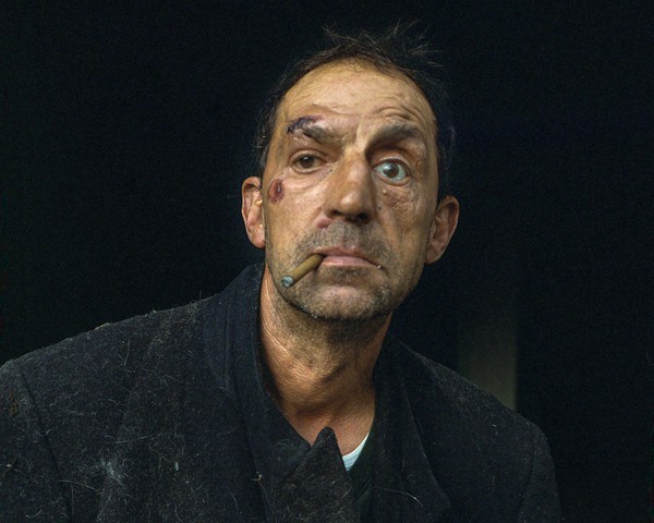 Tony solía llegar a casa con nueces, afirmando que se las había dado su novia, Rosemary. Sin embargo, Rosemary solo existía
										en su mente. Tony, primo de mi padre, vive en Atás, una pequeña aldea en la frontera entre Galicia y Portugal. Creció
										con padres alcohólicos y, por desgracia, él mismo se convirtió en alcohólico. Tony recuerda: «Cuando era niño, mi padre me
										ponía un vaso de vino en la mesa y me decía: “¡Bebe! Un poco no te hará daño”». Cuando Tony bebe alcohol pierde rápidamente
										el control, hasta el punto de haber perdido un ojo en un accidente de coche conduciendo ebrio. Actualmente ha
										perdido su trabajo debido al alcoholismo y vive de ayudas del Estado y de la caridad de su familia. La depresión de la zona,
										la falta de oportunidades laborales y las dificultades de comunicación hicieron aún más complicado que pudiera superar su
										adicción.
