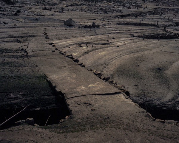 Entre las ruinas, los restos de un puente casi arrasado en A Reloeira evocan la idea cristiana del “Puente al Infierno”, un camino
										metafórico que separa la vida de la muerte y simboliza decisiones que conducen a consecuencias desastrosas. Galicia,
										tierra de misticismo y folclore, está profundamente ligada a leyendas de brujas, espíritus y rituales sagrados, donde las tradiciones
										paganas se entrelazan con la espiritualidad cristiana. Esta intersección entre lo místico y lo religioso configura la
										identidad gallega, arraigada en narrativas ancestrales y en un fuerte simbolismo espiritual.
										Galicia, conocida por sus creencias profundamente arraigadas y su rico folclore, ha sido históricamente una tierra impregnada
										de misticismo. Las leyendas de brujas, espíritus y rituales sagrados han moldeado su identidad cultural, fusionando
										tradiciones paganas y espiritualidad cristiana. Esta convivencia entre lo místico y lo religioso es perceptible en la población
										gallega, tanto en su simbología espiritual como en el peso de sus relatos ancestrales.