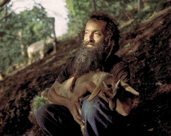 Nacho tiene 40 años y es originario de Zaragoza, una ciudad situada a casi 1.000 kilómetros de Galicia. Tras una juventud
										turbulenta, decidió aislarse en las montañas gallegas para vivir una vida menos dependiente de la sociedad. Hoy cuida de su
										rebaño de cabras, con las que mantiene un vínculo muy especial: las abraza, les habla y las cuida como si fueran sus hijos.
										Cada mañana las lleva temprano al monte para que pasten y no regresa a casa hasta el anochecer. En estos animales parece
										haber encontrado el sentido de su existencia. Nacho vive en una antigua casa de piedra ocupada, sin electricidad. Su alimentación
										se basa en verduras y en la leche que producen sus cabras. Como él mismo dice, su sueño sería comer como las
										cabras, alimentándose de las hierbas del monte. Nacho lleva una vida casi ermitaña, encontrando en esta autoexclusión de
										la sociedad normalizada una auténtica sensación de libertad.